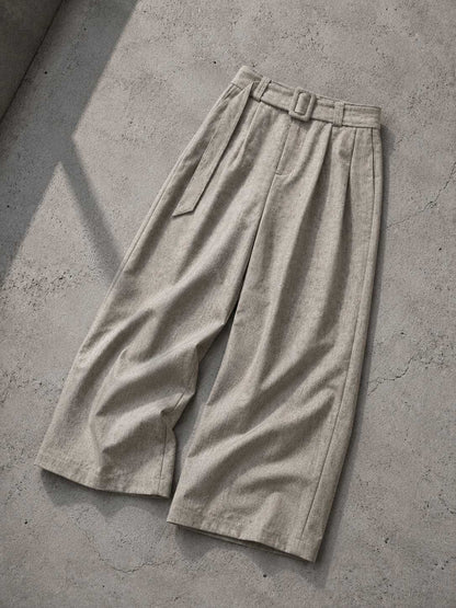 Beige wide-leg pants with a belt on a concrete surface