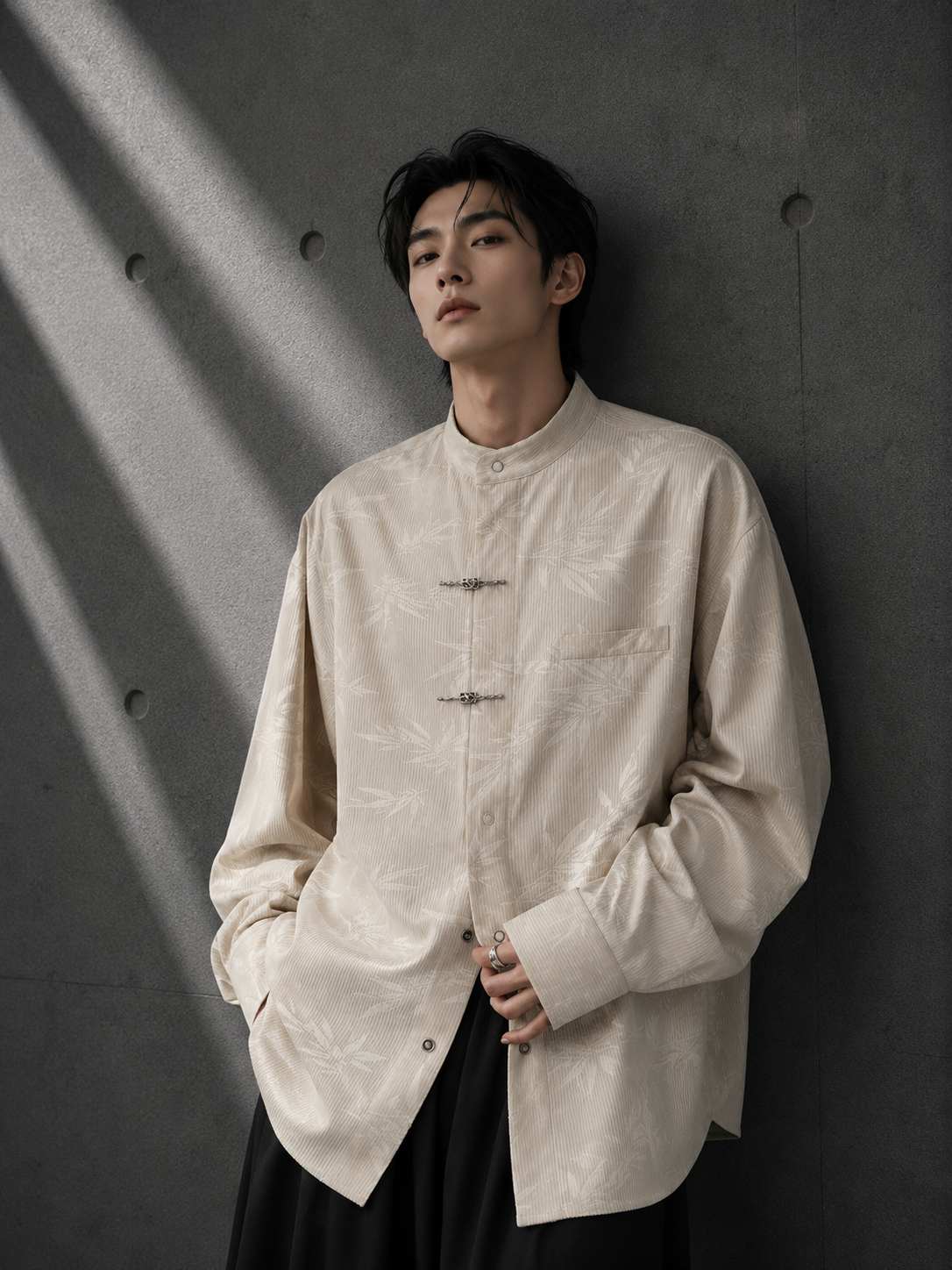 Person wearing a beige button-up shirt against a dark background