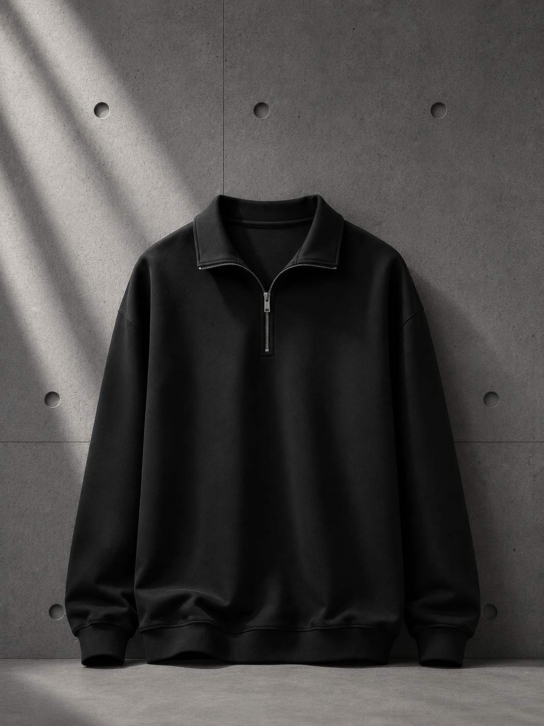 Black half-zip sweatshirt on a gray concrete background