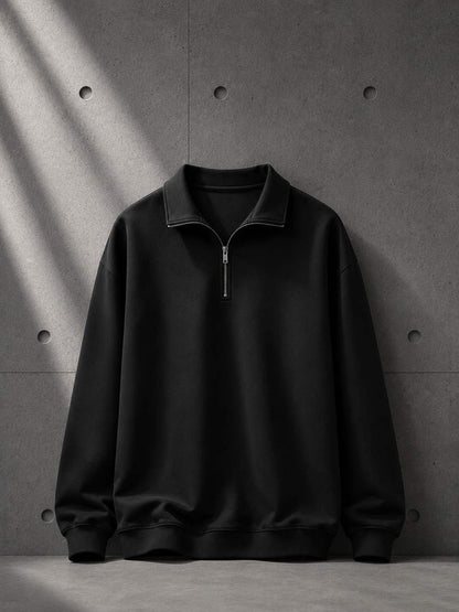 Black half-zip sweatshirt on a gray concrete background
