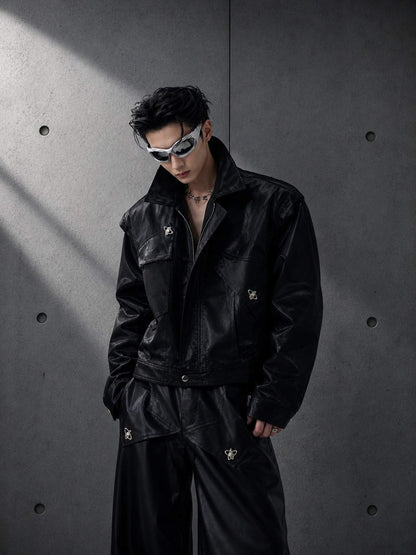 Person wearing a black jacket and pants with sunglasses against a gray concrete wall.