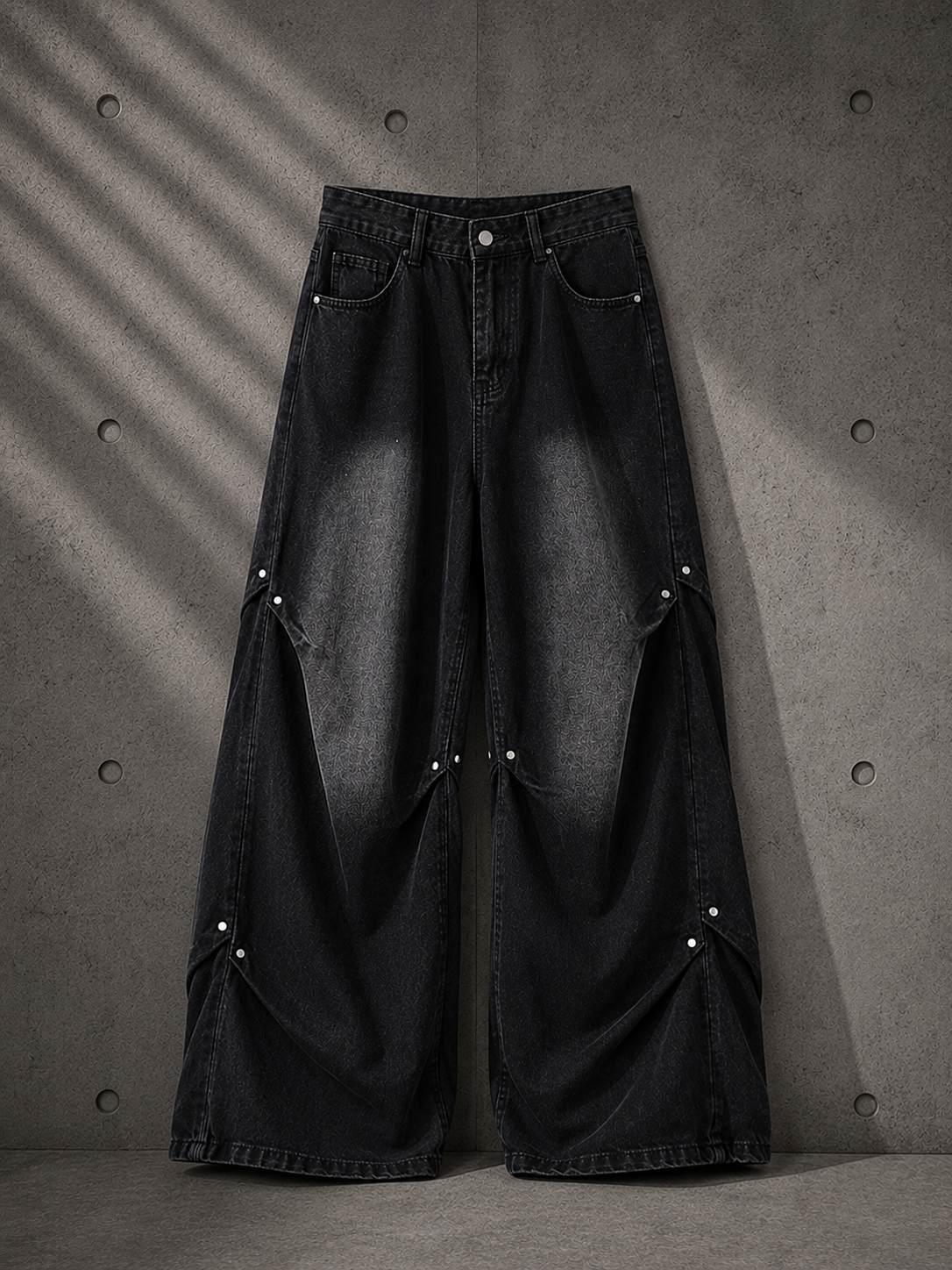 Black wide-leg jeans with pearl buttons on a textured gray background