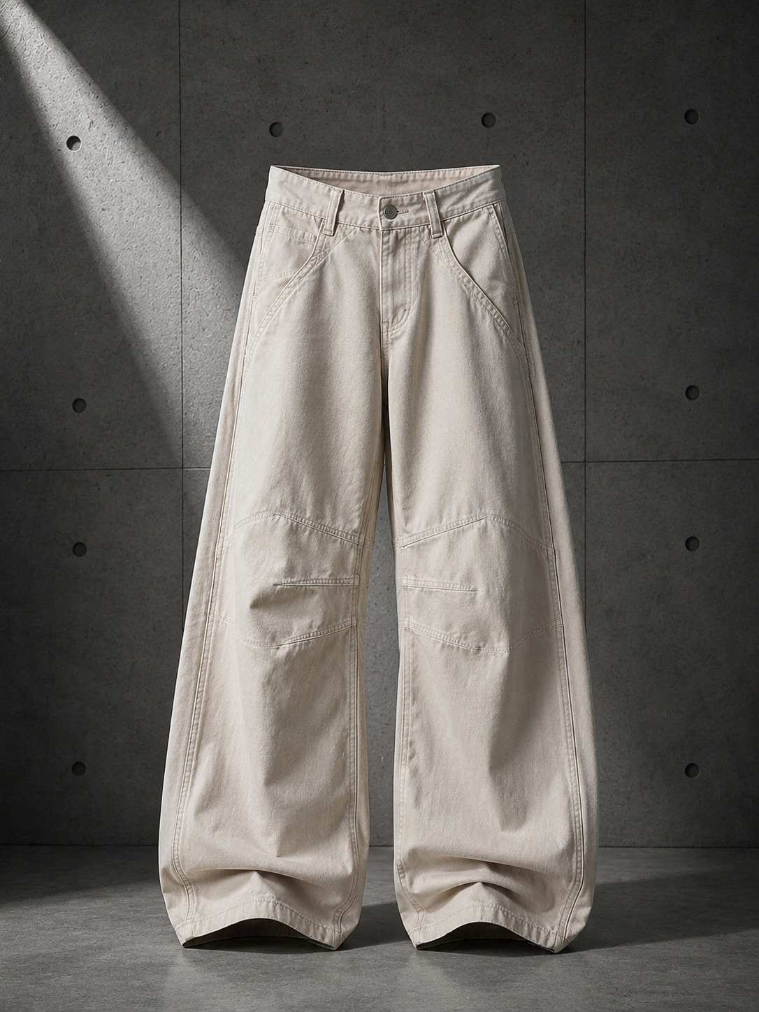 Beige wide-leg pants on a concrete floor with a gray wall background