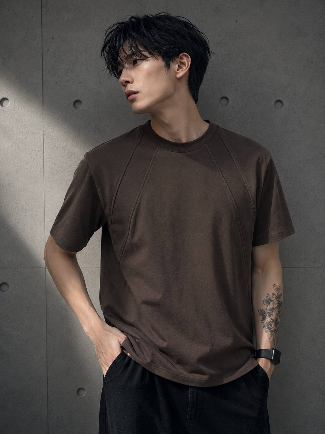 Man wearing a brown t-shirt against a gray concrete wall