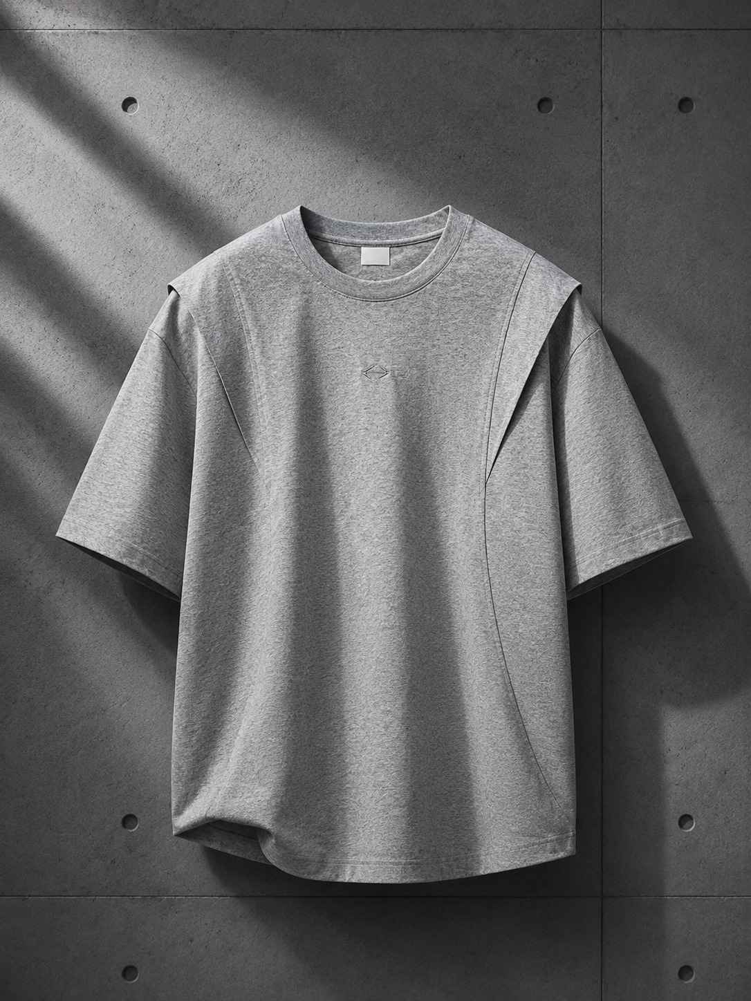 Gray t-shirt with a small logo on a concrete wall background