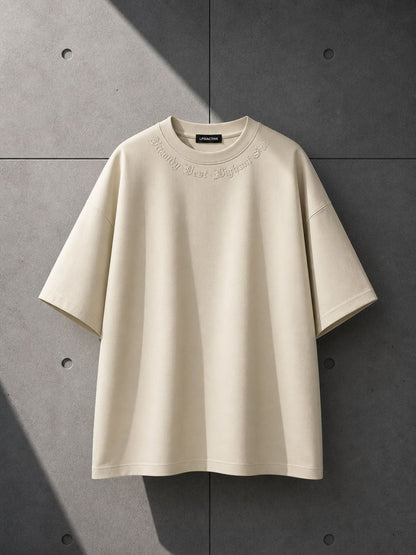 Beige t-shirt with text on a gray concrete wall