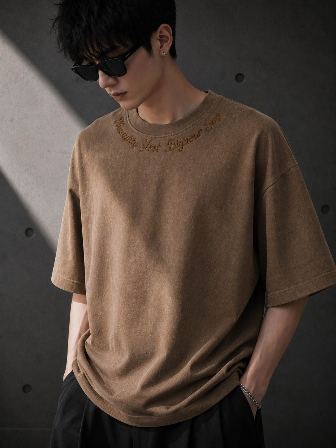 Person wearing a brown t-shirt with text on a dark background