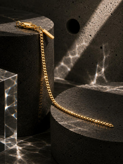 Gold chain necklace on a black pedestal with a marble background