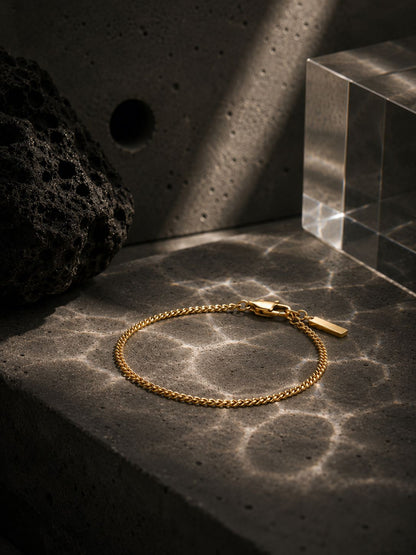 Gold bracelet on a textured stone surface with a dark background