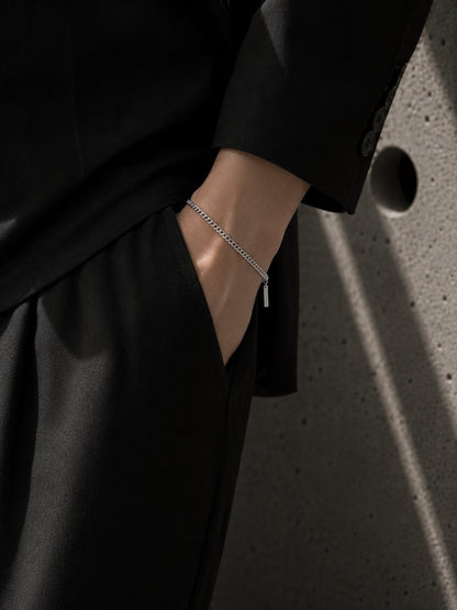 Person wearing a black outfit with a bracelet on a textured surface