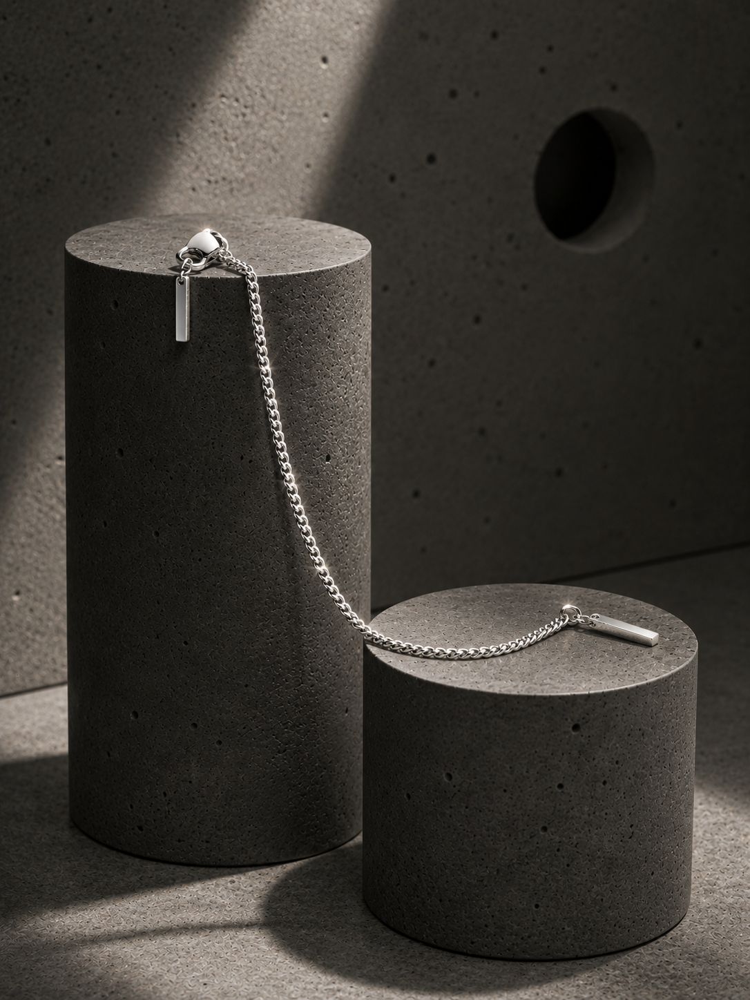 Silver chain necklace on a concrete surface with a concrete block background