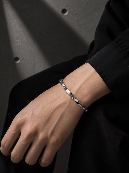Hand wearing a silver bracelet on a dark background