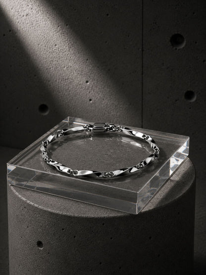 Silver bracelet on a clear stand against a concrete background