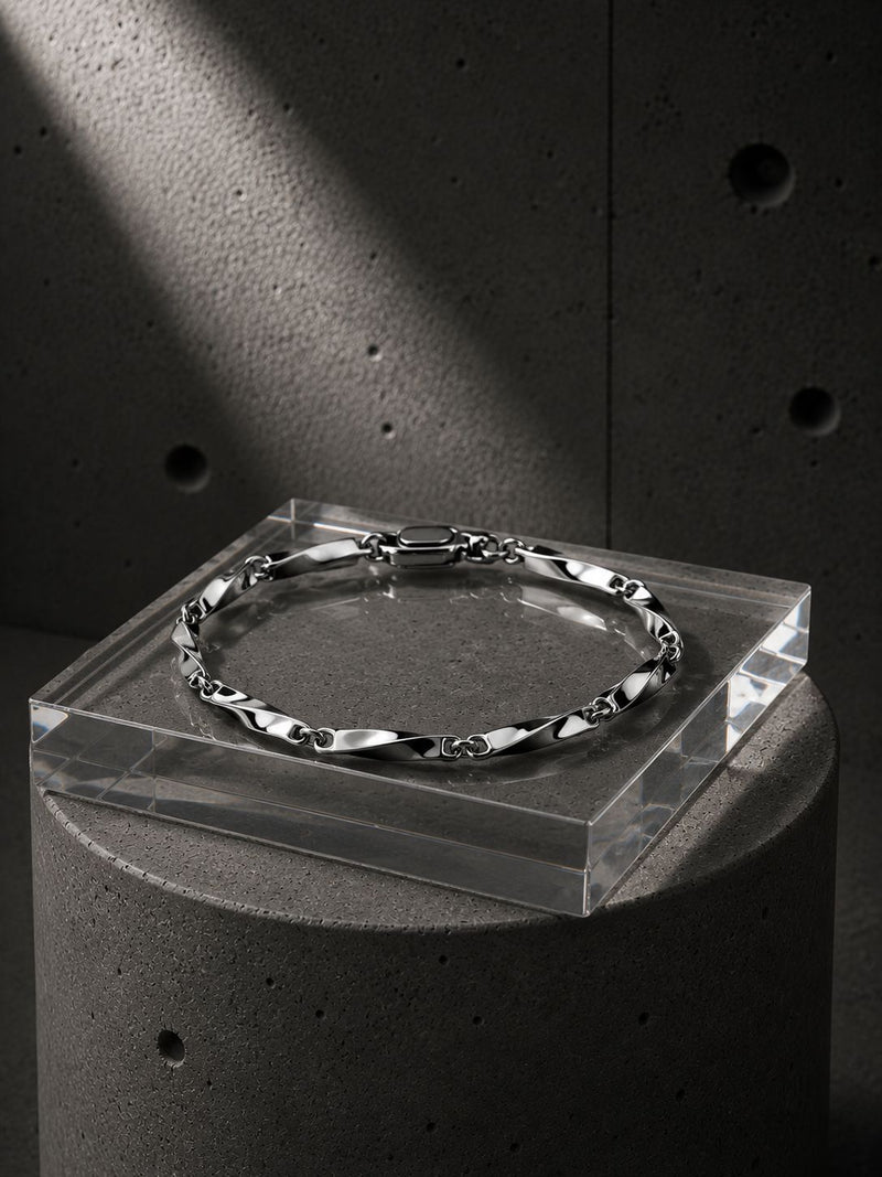 Silver bracelet on a clear stand against a concrete background