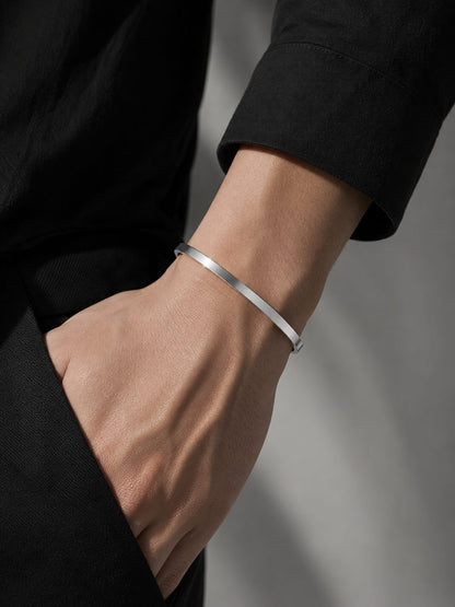 Silver bracelet on a person's wrist with a neutral background