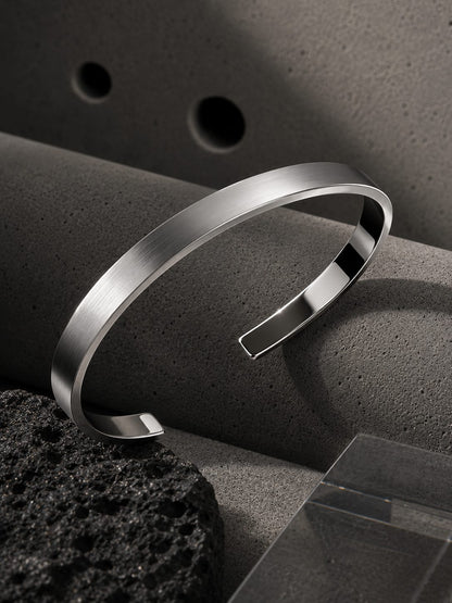 Silver bracelet on a textured surface with a dark background