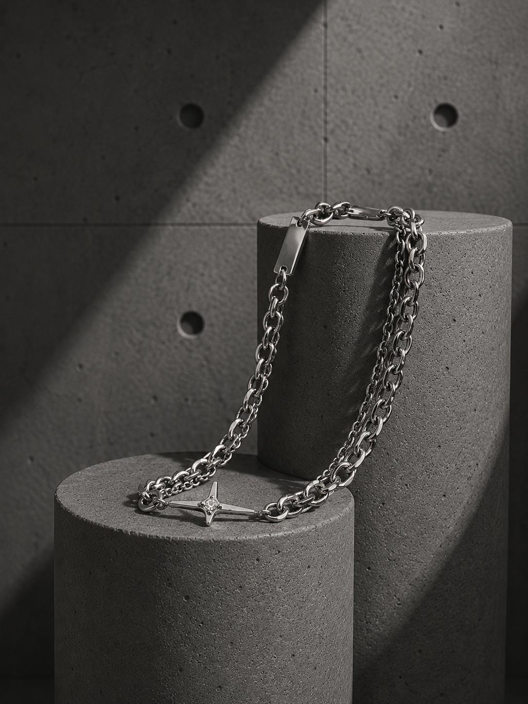 Silver chain necklace on a concrete surface with a concrete wall background