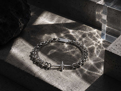 Silver chain bracelet with a star charm on a textured stone surface
