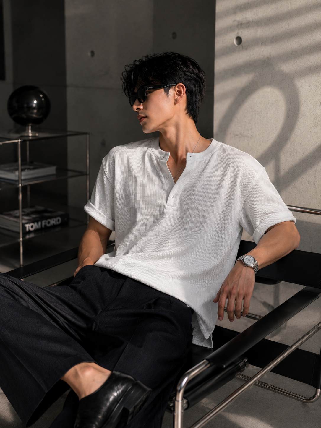 Man wearing a white shirt and black pants sitting in a modern chair.