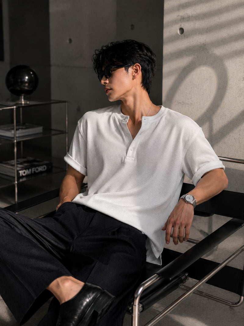 Man wearing a white shirt and black pants sitting in a modern chair.